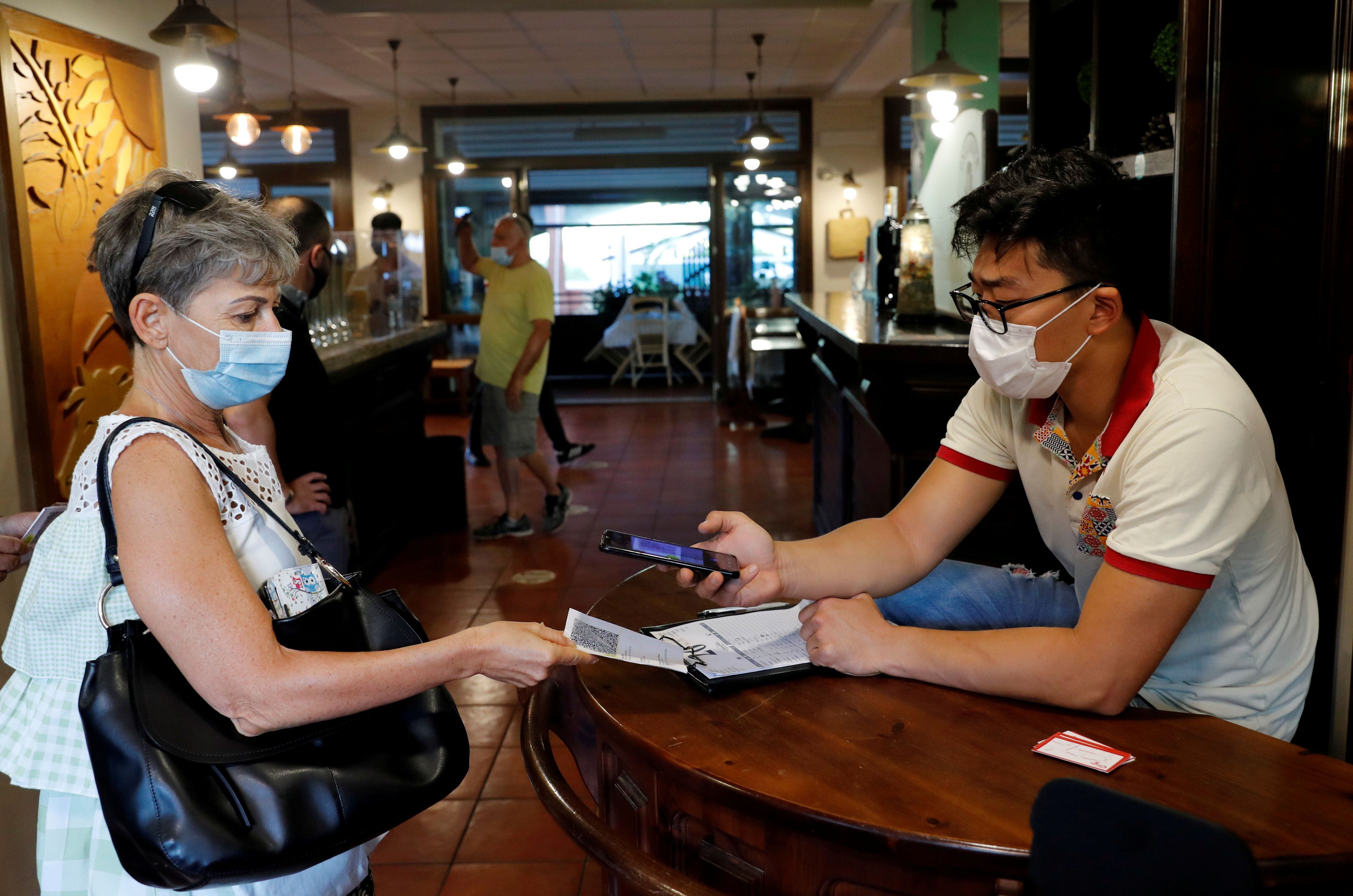 Foto de archivo: Una mujer hace revisar su Green Pass (tarjeta sanitaria) antes de entrar en una pizzería en Roma, Italia (Foto: REUTERS/Remo Casilli)