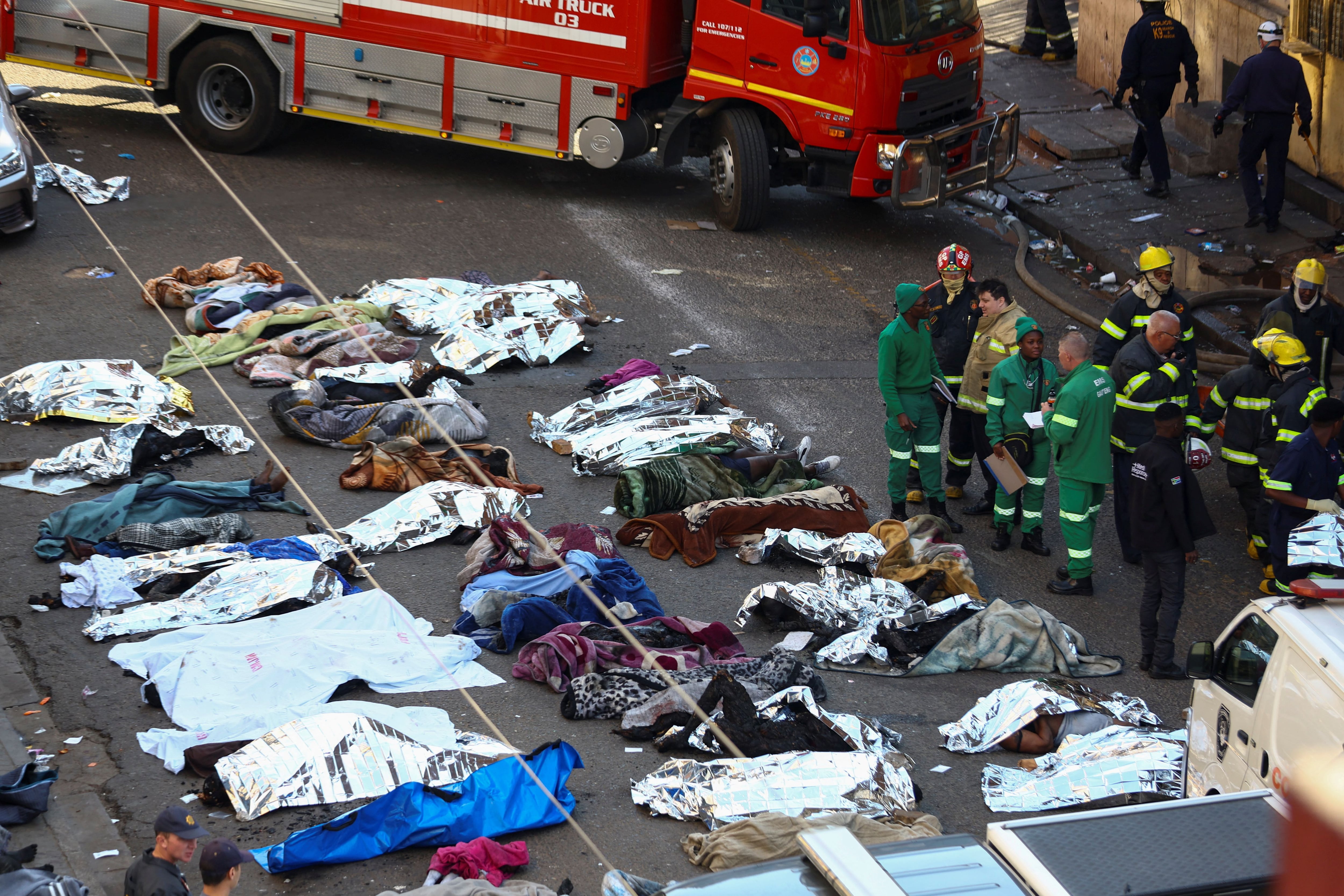 Rescatistas y bomberos junto a los cuerpos de las víctimas del incendio que tuvo lugar en Johannesburgo, Sudáfrica, el 31 de agosto 2023 (REUTERS/Siphiwe Sibeko)