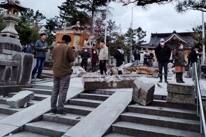 Un grupo de personas junto a una puerta torii derrumbada por un terremoto en el santuario de Onohiyoshi, en Kanazawa. (Kyodo via REUTER)