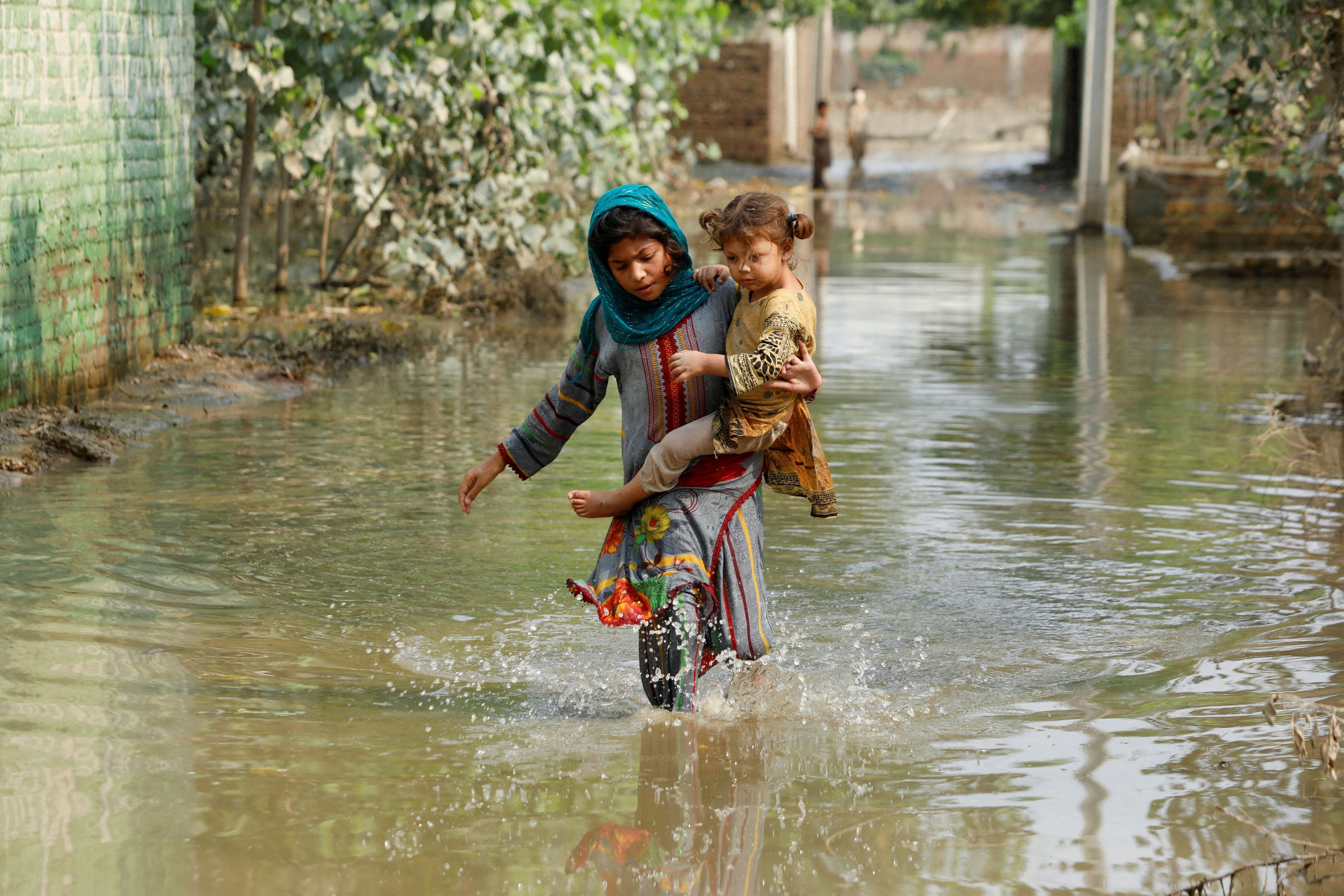 Una niña lleva a su hermano mientras camina a través de agua de inundación varada, después de las lluvias e inundaciones durante la temporada del monzón en Nowshera, Pakistán 4 de septiembre de 2022. REUTERS/Fayaz Aziz/Archivo