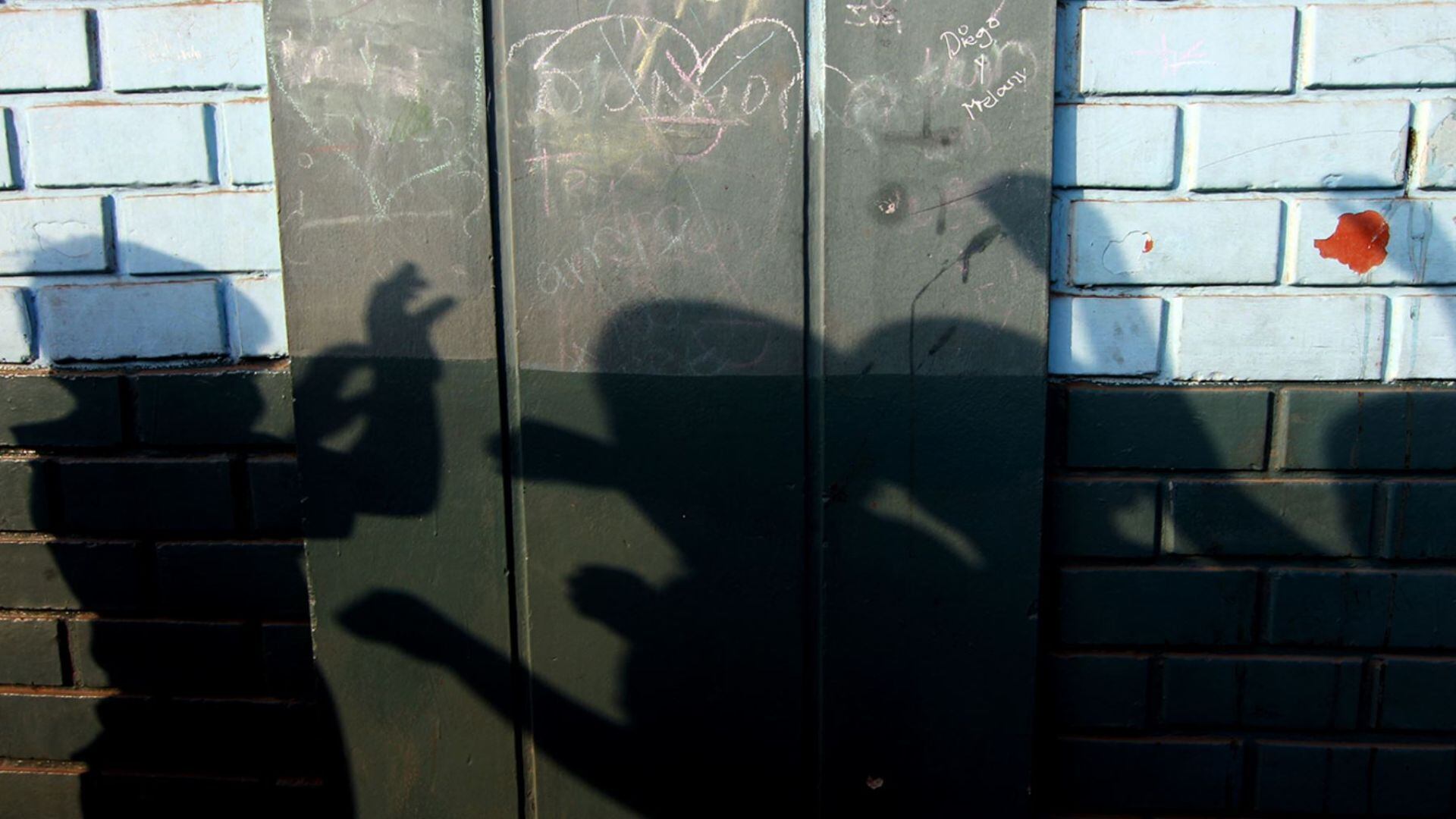 Imagen de niños cubriéndose el rostro y sombras que representan la violencia escolar.