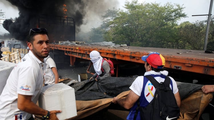 Venezolanos intentan vaciar uno de los camiones con alimentos y remedios que fue quemado por orden de Nicolás Maduro (Reuters)