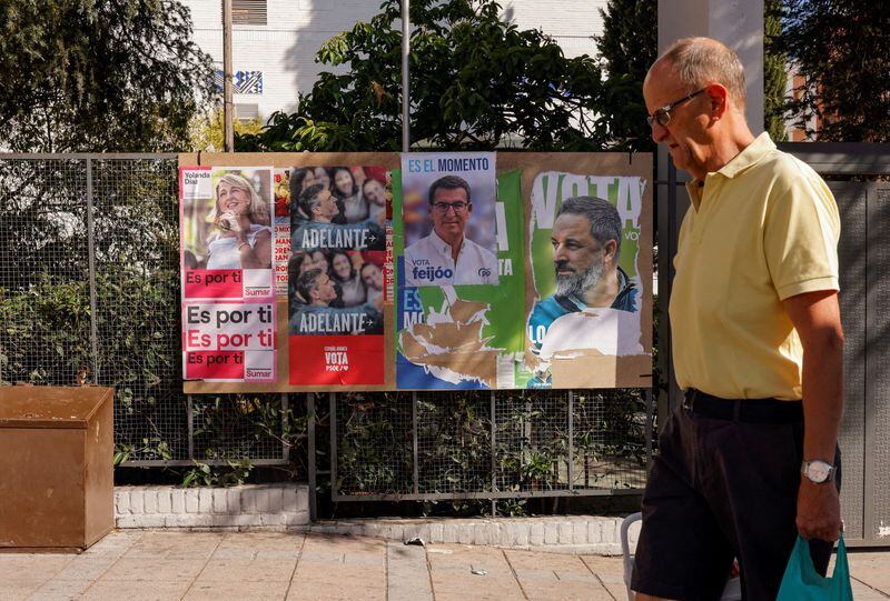 Un hombre camina junto a los carteles electorales de los líderes políticos. 