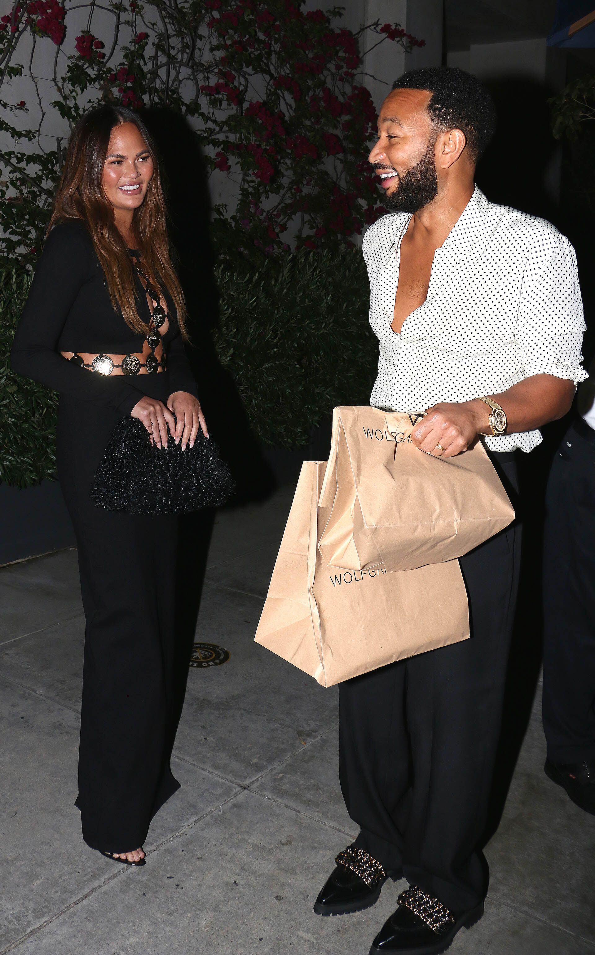 Noche romántica. Chrissy Teigen y John Legend fueron a comer a un exclusivo restaurante de Beverly Hills y los fotografiaron cuando salían del local cargando las bolsas con comida para llevar. Ella lució un look total black, mientras que él optó por un pantalón del mismo color y una camisa blanca con lunares negros