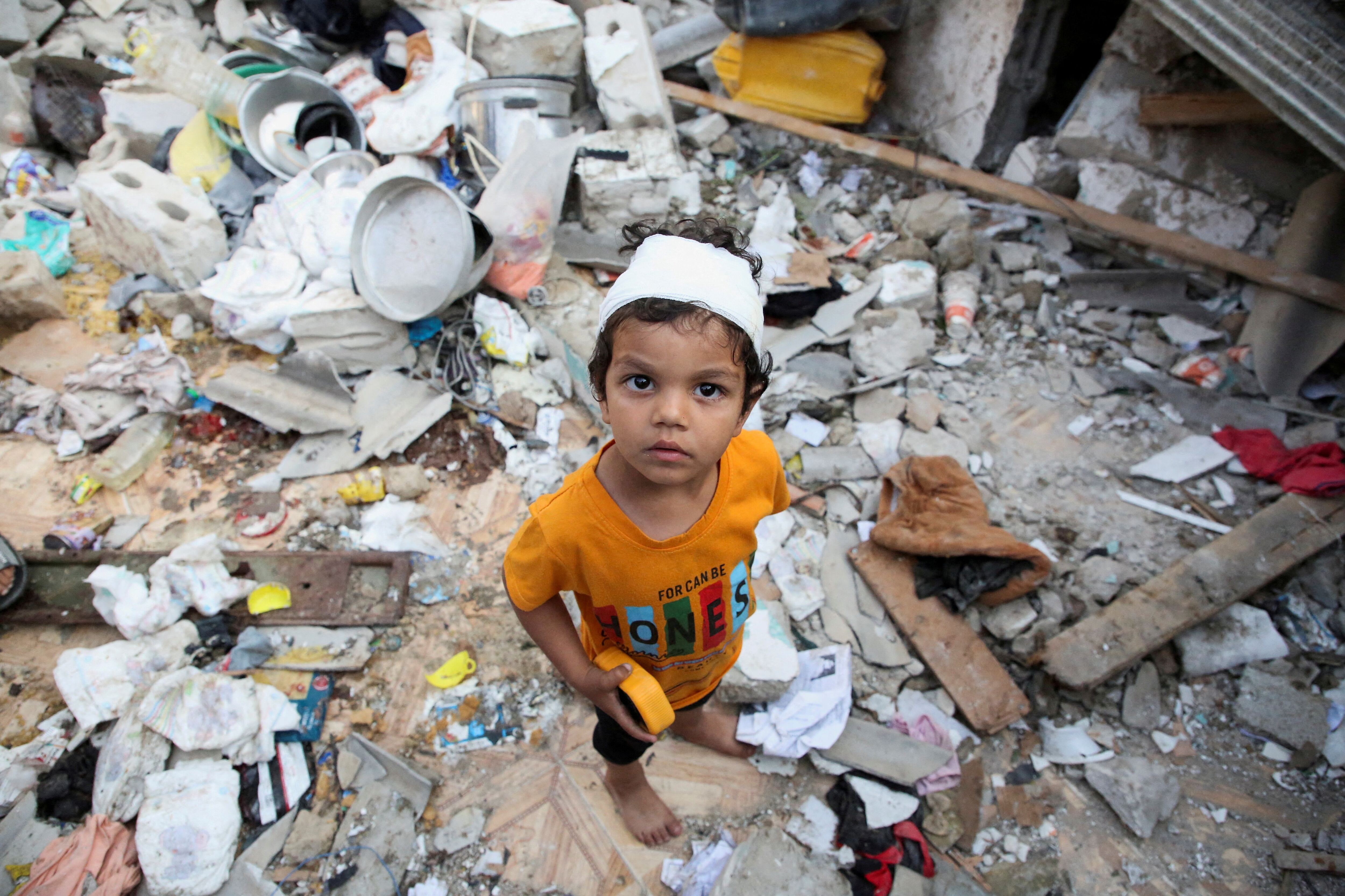 Un niño palestino busca objetos entre los restos de un edificio dañado por un bombardeo en Rafah, al sur de la Franja de Gaza (REUTERS/Hatem Khaled)