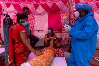 Una mujer rodeada de sus familiares recibe soporte de oxígeno en un Gurudwara (templo sij), en medio de la propagación de la enfermedad del coronavirus (COVID-19), en Ghaziabad, India, el 6 de mayo de 2021. REUTERS/Danish Siddiqui