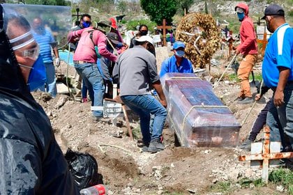 Trabajadores municipales fueron registrados el pasado jueves al introducir a una fosa un féretro desinfectado en el panteón de San Isidro, en el municipio de Ecatepec (México). EFE/Jorge Núñez
