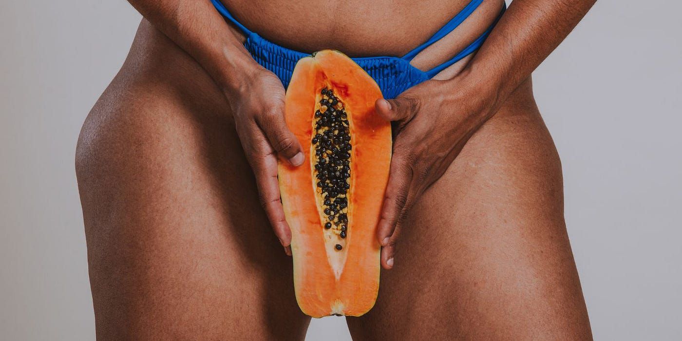 Una mujer en ropa interior con una papaya delante simbolizando la vulva - Cunnilingus (Medium)