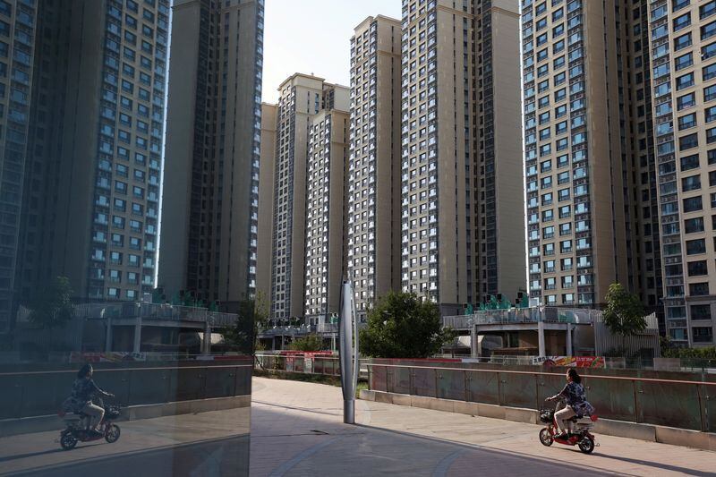 Una mujer conduce una motocicleta frente a edificios residenciales en un complejo residencial de Evergrande en Beijing. (REUTERS/Florence Lo/Foto de archivo)