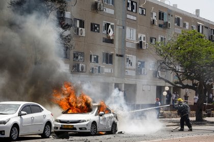 I vigili del fuoco israeliani hanno spento l'incendio di un'auto colpita da un missile palestinese ad Ashkelon (Reuters / Nir Elias).