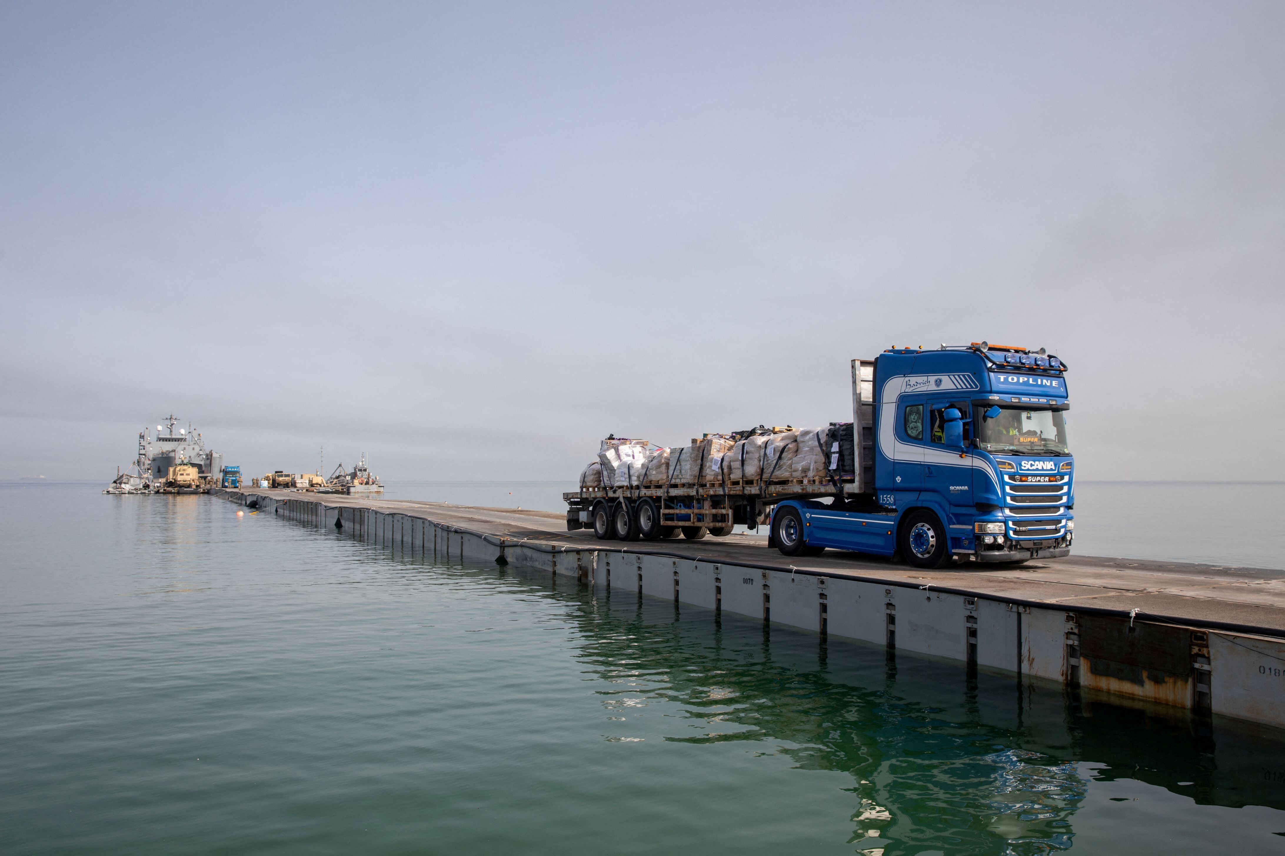 Un camión transporta ayuda humanitaria a través de Trident Pier, un muelle temporal para entregar ayuda cerca de la costa de Gaza el 19 de mayo de 2024 (REUTERS)