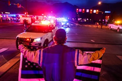 Un hombre sostiene una bandera de línea azul delgada mientras vehículos de emergencia escoltan el cuerpo del oficial de policía asesinado Eric Talley desde la escena de un tiroteo en una tienda de comestibles King Soopers en Boulder, Colorado (Reuters)