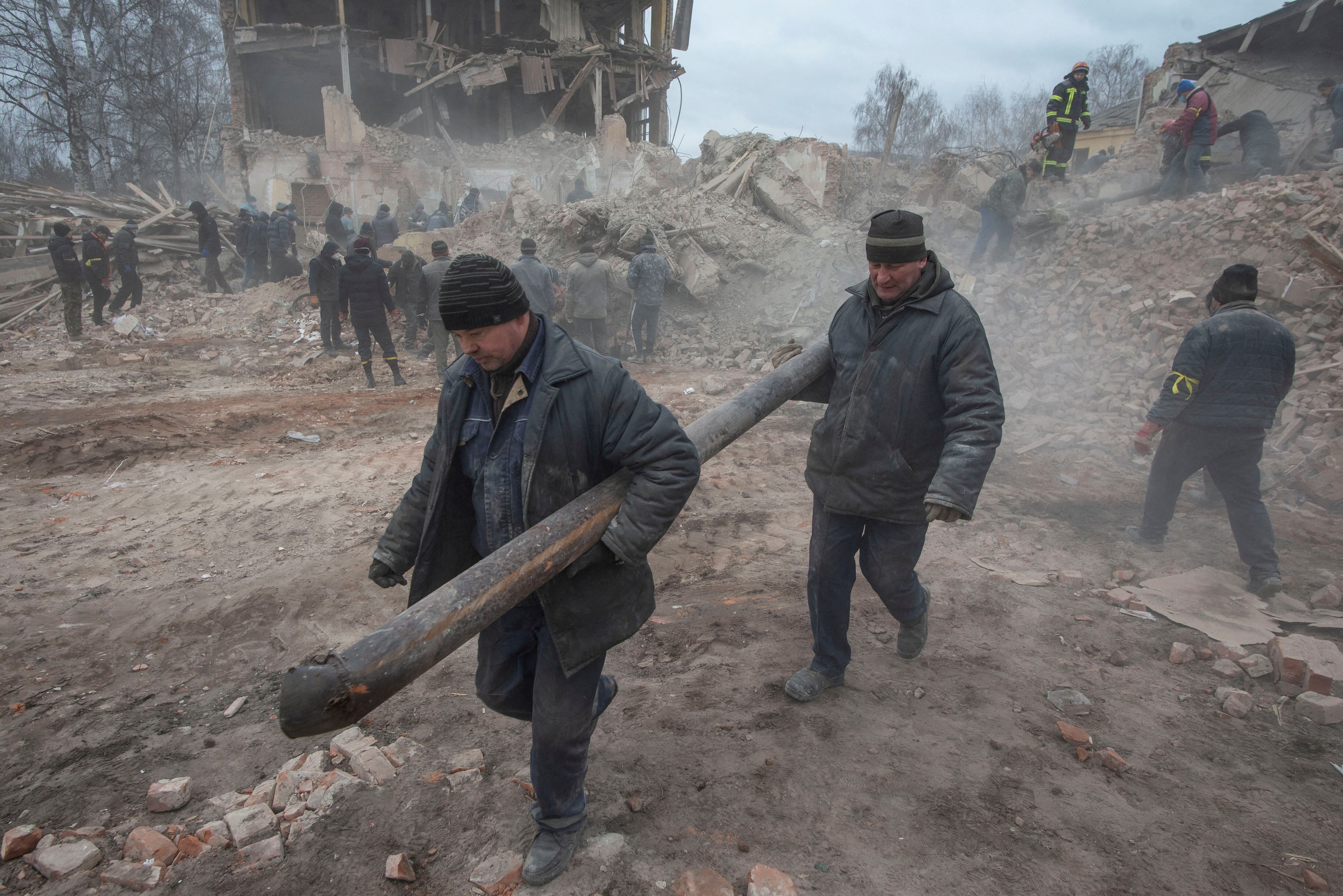 Personas retiran escombros en el sitio del edificio de una base militar que, según las fuerzas terrestres ucranianas, fue destruida por un ataque aéreo, en la ciudad de Okhtyrka en la región de Sumy, Ucrania, el 28 de febrero de 2022. (Irina Rybakova/Servicio de prensa de las fuerzas terrestres ucranianas/REUTERS)