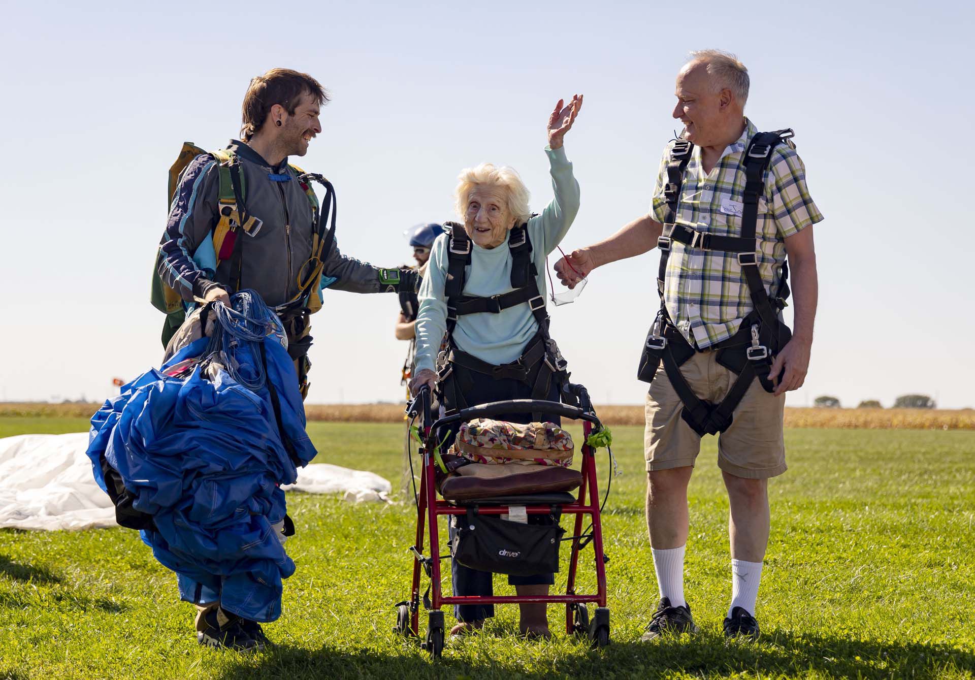 Dorothy Hoffner, de 104 años, saluda a la multitud con el saltador en tándem Derek Baxter, a la izquierda, y su amigo Joe Conant, en Skydive Chicago en Ottawa, Illinois (Brian Cassella/Chicago Tribune via AP)