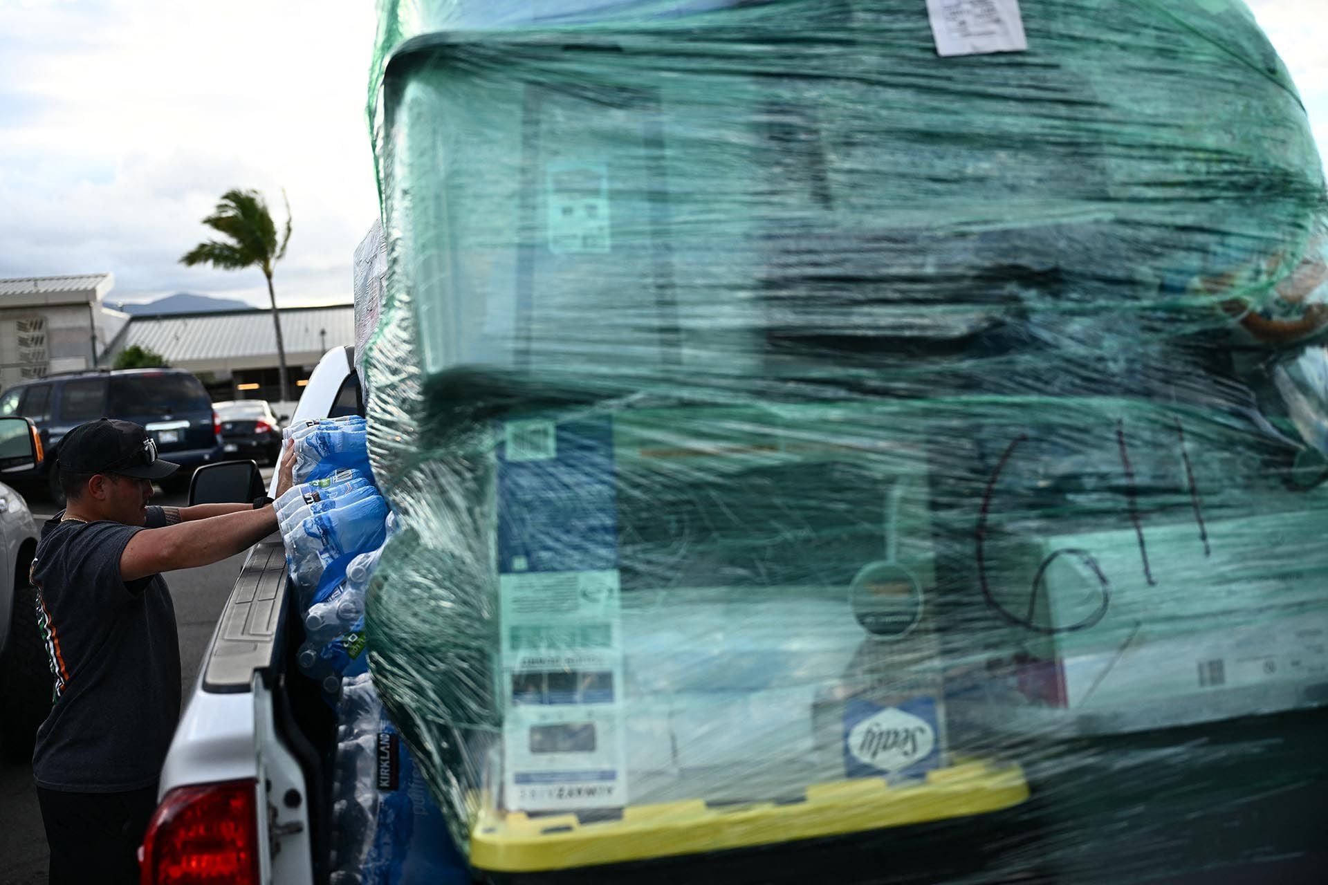 Los voluntarios cargan paletas de suministros y donaciones de ayuda que llegaron desde la isla hawaiana de Kauai en camionetas en la terminal de carga del aeropuerto de Kahului después de los incendios forestales de Maui en Kahului, Hawái, el 13 de agosto de 2023. (Foto de Patrick T. Fallon / AFP)