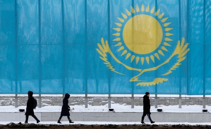 Varias personas pasan frente a la bandera de Kazajistán en Astaná, Kazajistán, el 5 de marzo de 2019. REUTERS/Pavel Mikheyev