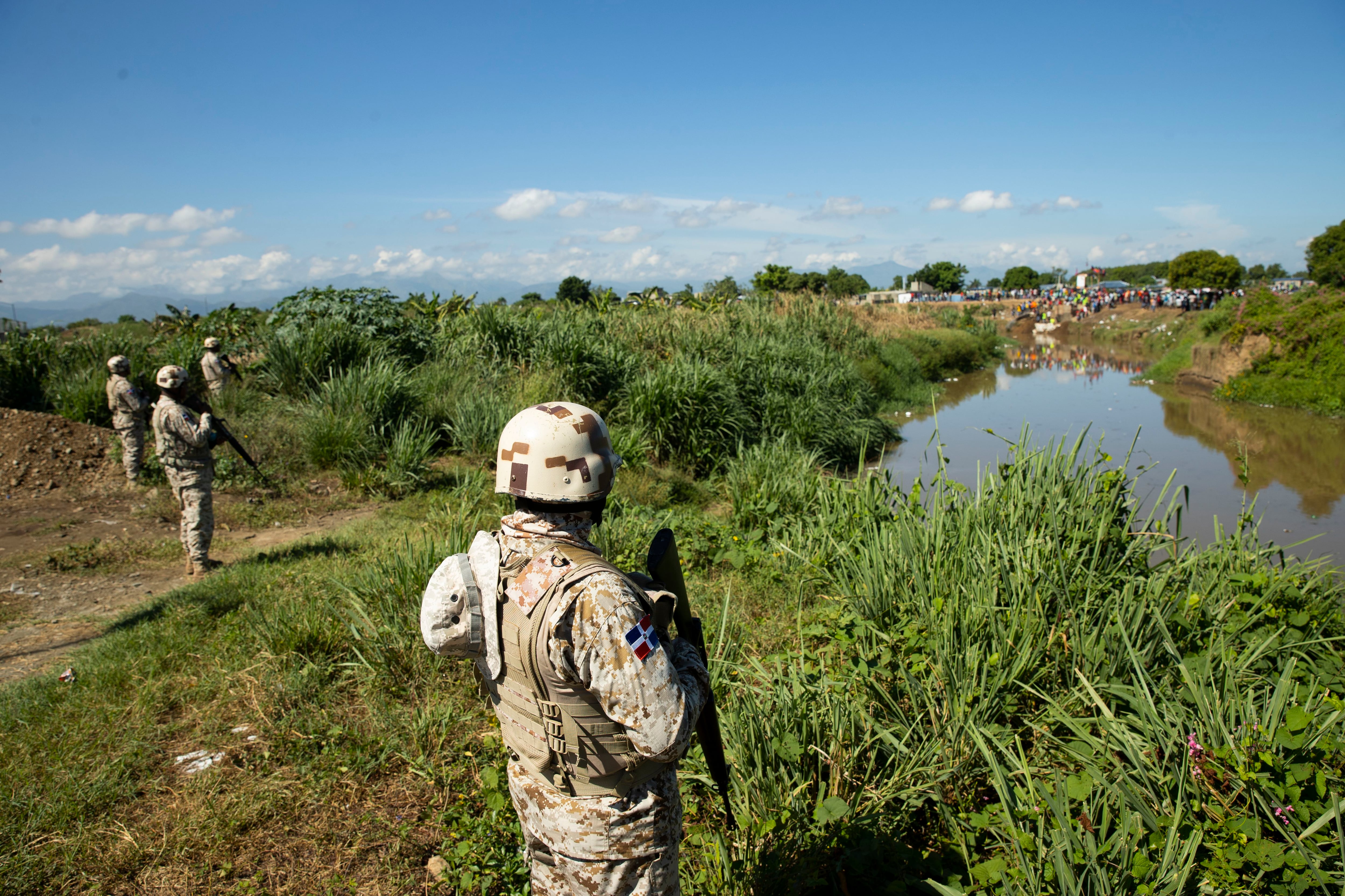 Miembros del Cuerpo Especializado en Seguridad Fronteriza Terrestre (Cesfront) de República Dominicana vigilan mientras en la orilla haitiana del río Masacre trabajadores construyen un canal de riego. EFE/Orlando Barría
