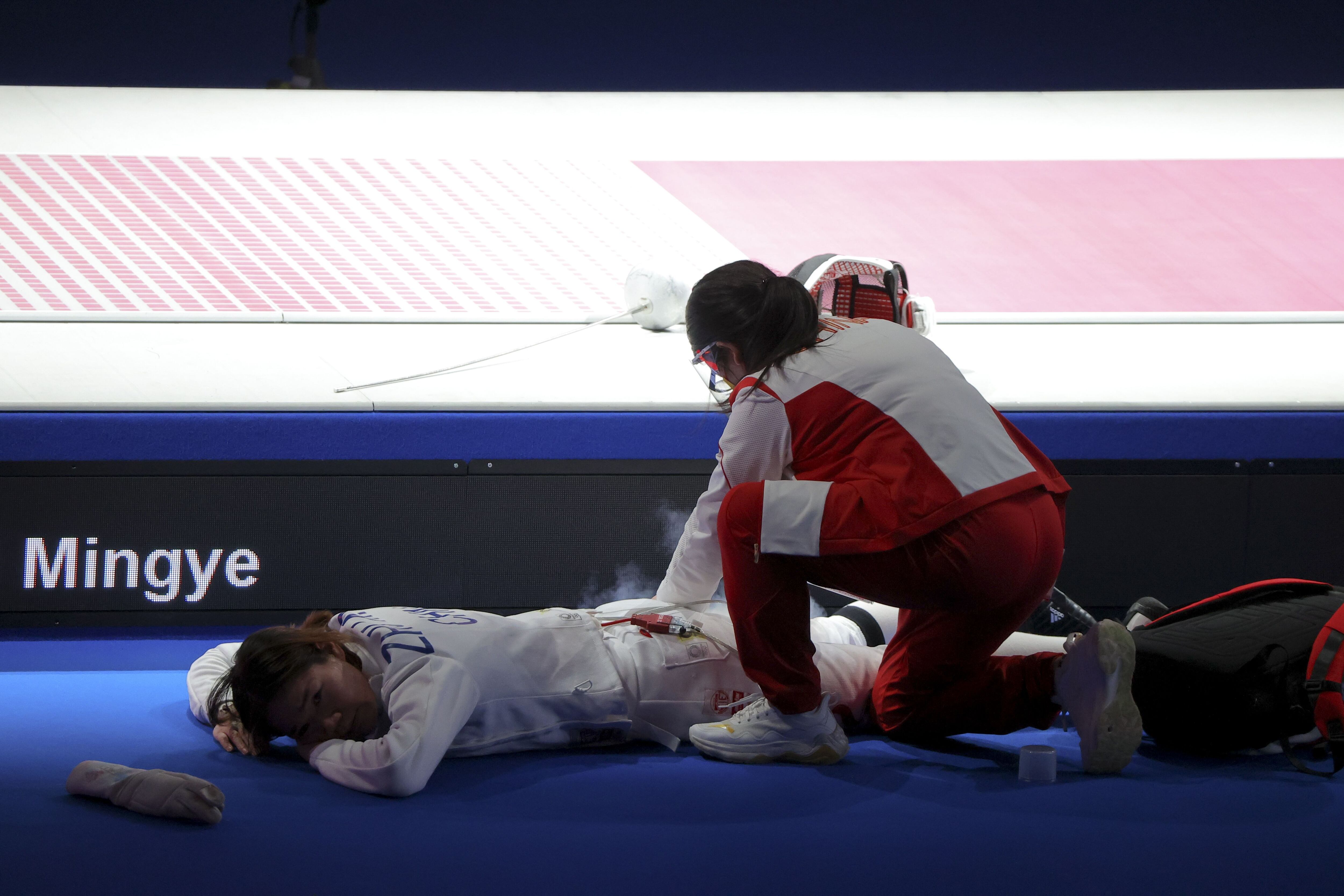 Mingye de China, es atendida después de sufrir una lesión, después de contender en esgrima espada por equipos femenina.