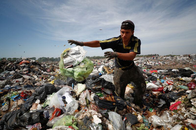 Diego, un joven de 19 años, revuelve la basura en Luján el 5 de octubre. Busca cartones, plásticos y metales para vender como forma de sobrevivir a una inflación que rondará el 100% este año en Argentina. Según el INDEC, en el primer semestre del año la pobreza alcanzó al 40,6% de la población, mientras que la indigencia al 10,7 (REUTERS/Agustín Marcarian)