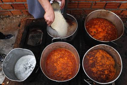 El cocinero Walter Ferreira vierte arroz en un estofado en un comedor social en Luque, Paraguay, el lunes 11 de mayo de 2020. El número de comedores benéficos en el país se ha multiplicado, después de que la cuarentena contra la pandemia de coronavirus paralizara la economía del país. (AP Foto/Jorge Saenz)