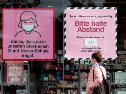El escaparete de una tienda de Berlín informa de las recomendaciones sobre el uso de mascarilla, la distancia de seguridad y el aforo máximo en el interior del establecimiento. EFE/EPA/HAYOUNG JEON
