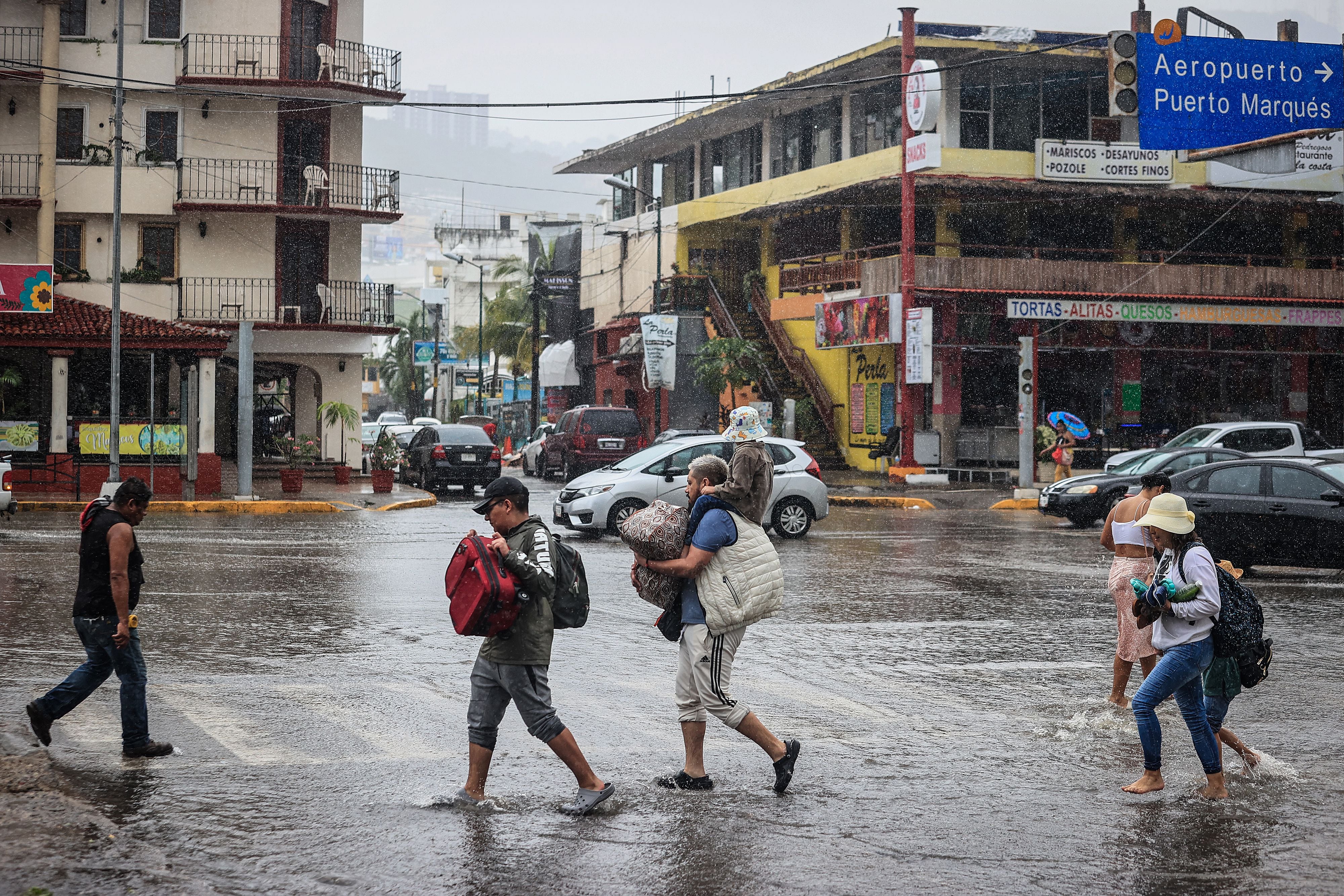 Personas caminan por una calle encharcada debido a las fuertes lluvias. EFE/David Guzmán
