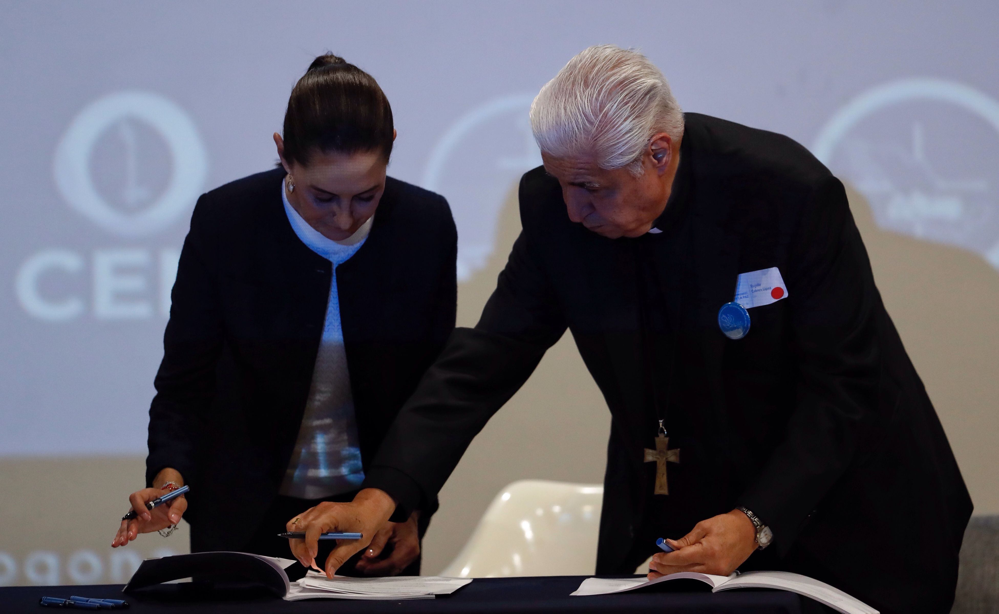 La candidata del oficialista Movimiento Regeneración Nacional (Morena) a la presidencia de México, Claudia Sheinbaum (i), y el presidente del Episcopado mexicano, Rogelio Cabrera (d), firman el compromiso por la paz este lunes, en Ciudad de México (México). EFE/Sáshenka Gutiérrez 