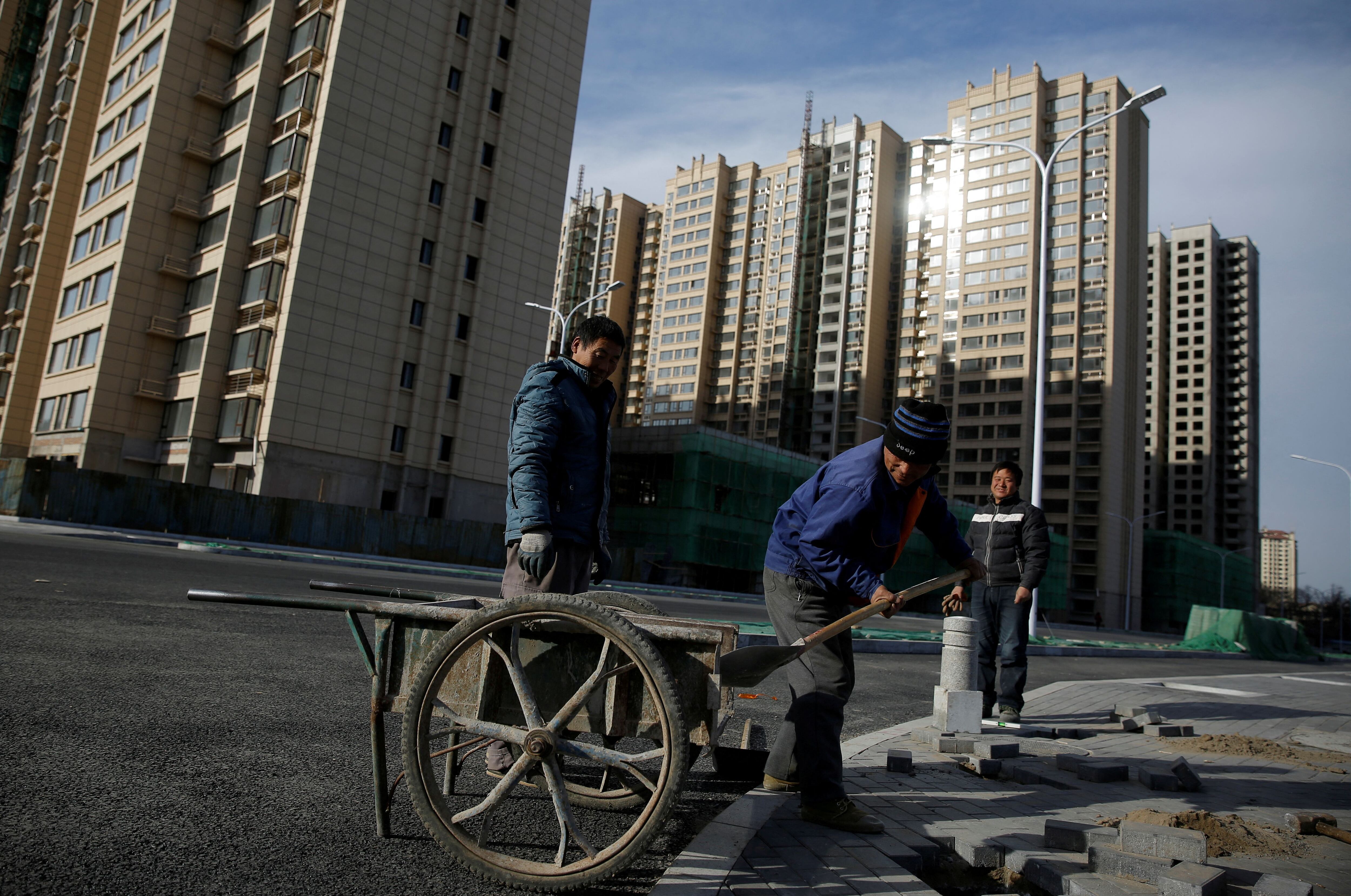 Hombres trabajan cerca de bloques de apartamentos residenciales en construcción en las afueras de Beijing (REUTERS/Thomas Peter/Foto de archivo)