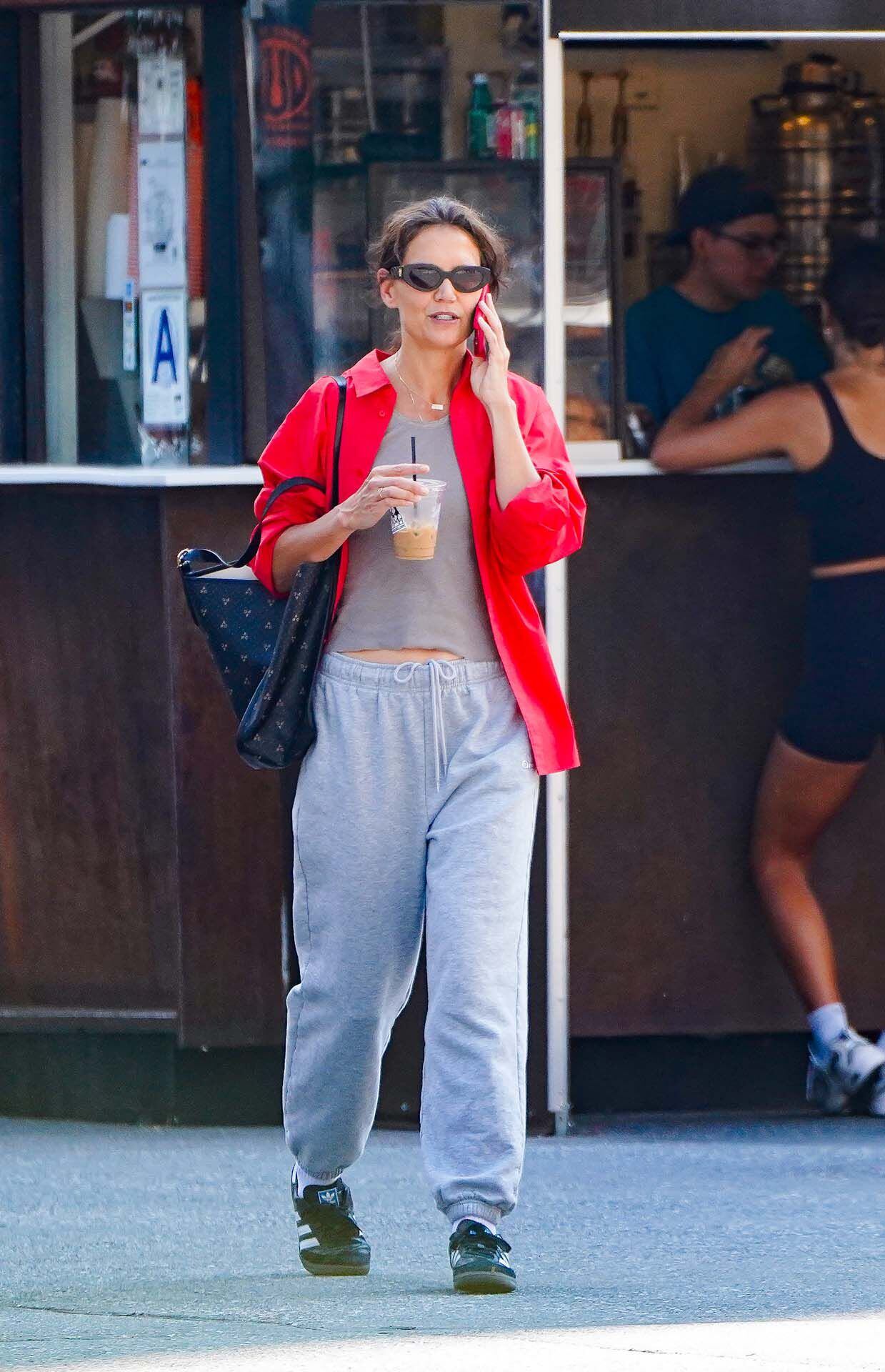 Katie Holmes fue descubierta por la prensa local mientras daba un paseo por las calles de su vecindario en Nueva York y hablaba por teléfono después de haber comprado un café helado para llevar. Vistió un conjunto de remera y pantalón gris de algodón y lo combinó con una camisa roja que usó abierta