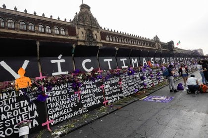 Mujeres se preparan para colocar flores junto a los nombres de víctimas de feminicidio en México frente a las vallas colocadas rodeando el Palacio Nacional antes de una protesta por el Día Internacional de la Mujer, en Ciudad de México, México. 7 de marzo de 2021. REUTERS/Toya Sarno Jordan