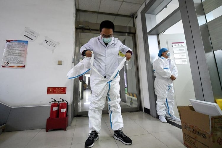 Un trabajador se pone su traje protector antes de entrar en un laboratorio de un centro de control y prevención de enfermedades, mientras el país se ve afectado por un brote del nuevo coronavirus, en Taiyuan, provincia de Shanxi, China, el 14 de febrero de 2020. cnsphoto via REUTERS