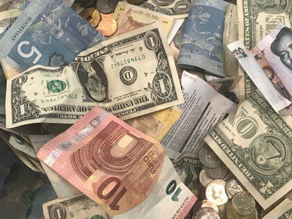 FILE PHOTO: U.S. dollars and other world currencies lie in a charity receptacle at Pearson international airport in Toronto, Ontario, Canada June 13, 2018. REUTERS/Chris Helgren