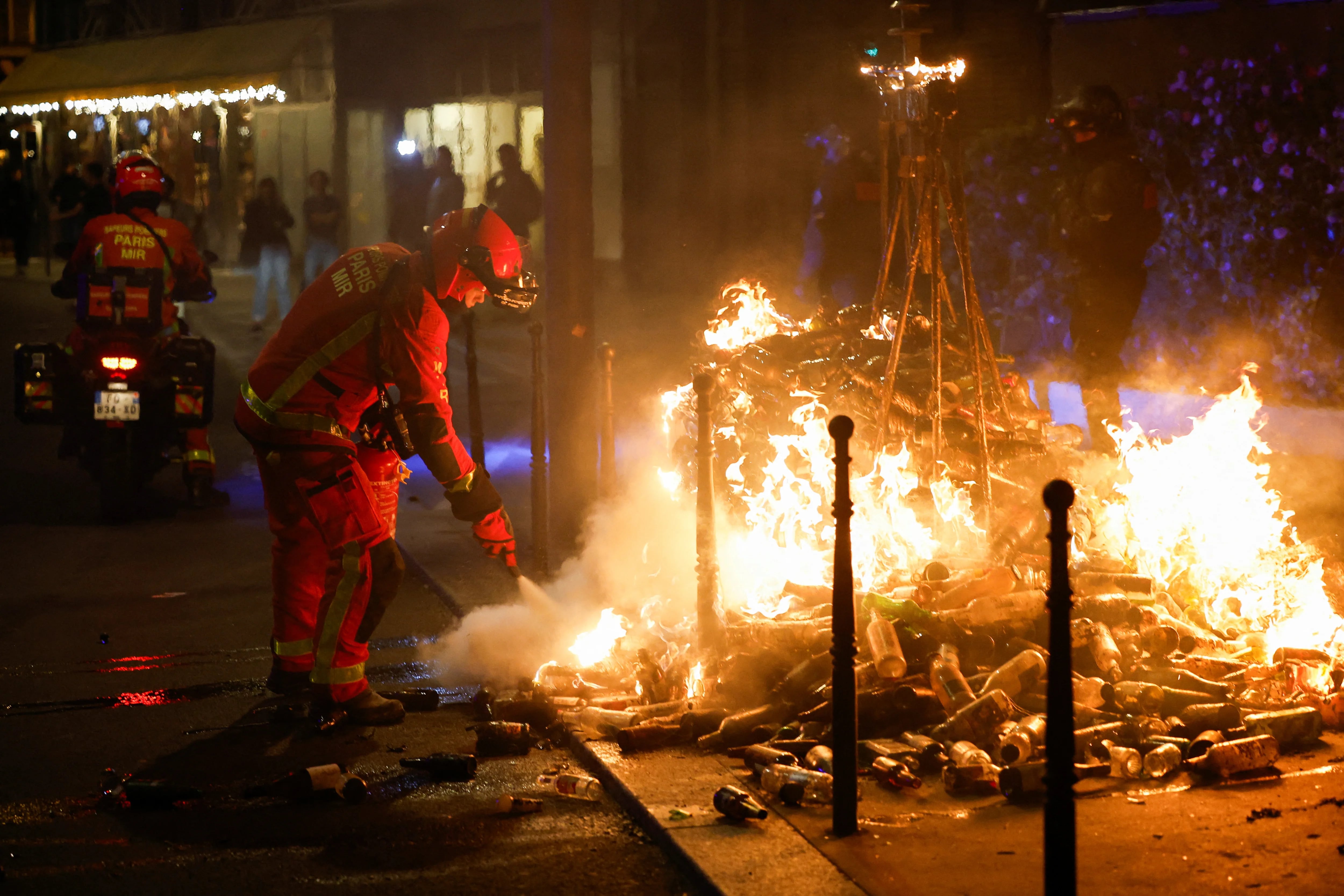 Un bombero extingue un fuego sobre una pila de botellas en el marco de las protestas en París (Reuters)