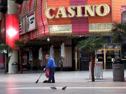 Un trabajador barre la vereda frente a un casino de Las Vegas, EEUU, cuyos negocios han quedado vacíos por las medidas para frenar la pandemia (REUTERS/Steve Marcus)