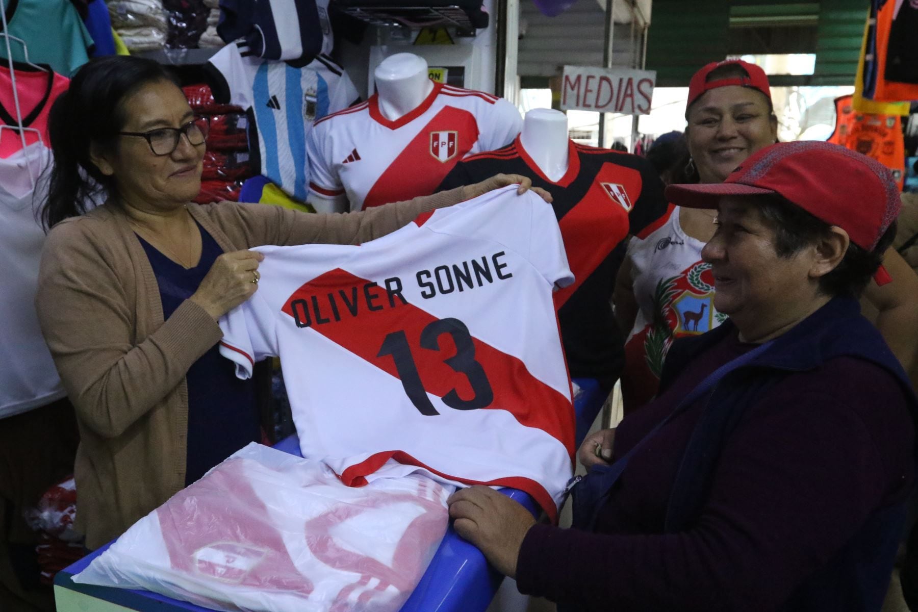 Una vendedora del emporio comercial de Gamarra ofrece la camiseta de Oliver Sonne a una compradora interesada en llevar la prenda para su hijo.