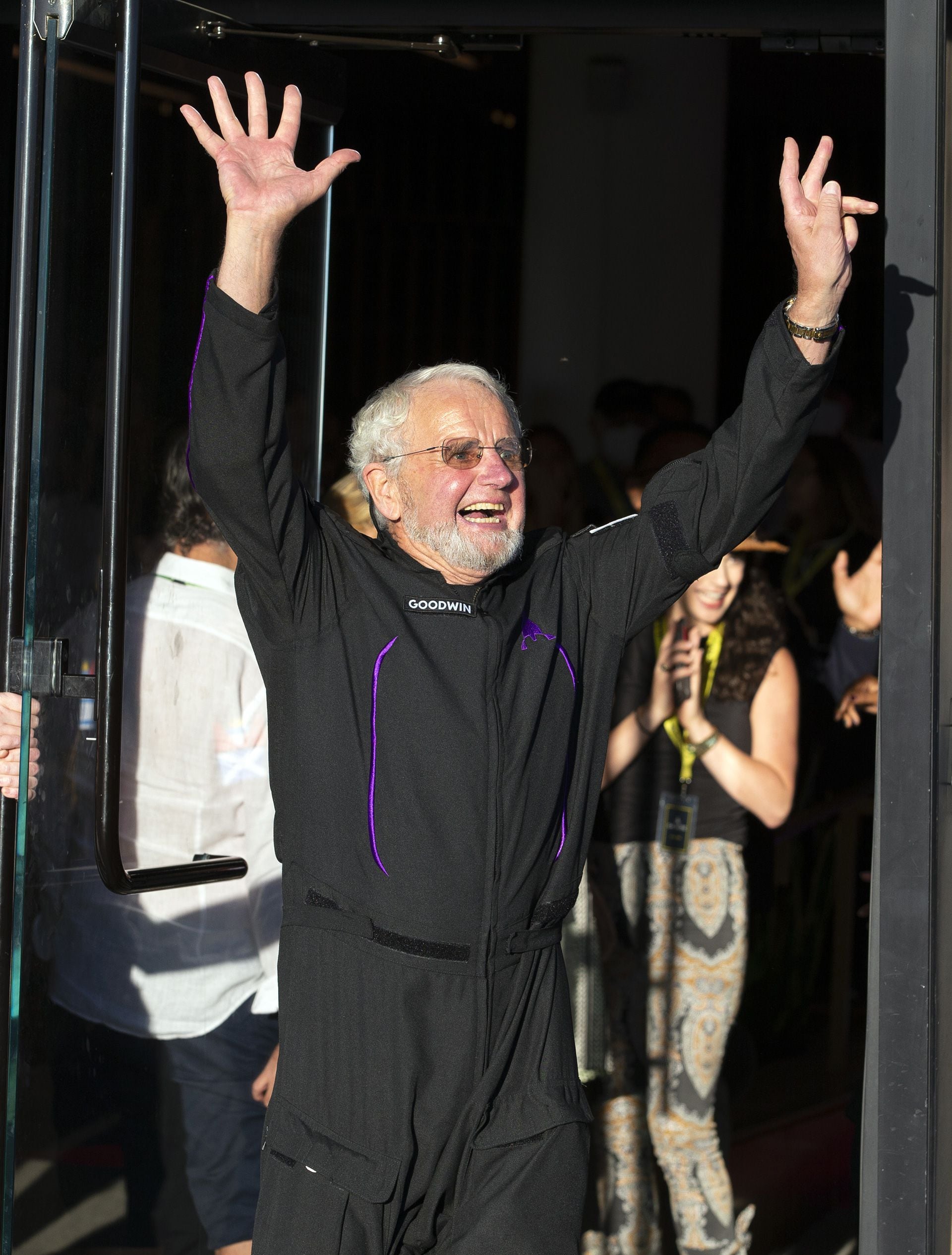 Space tourist Jon Goodwin, an 80-year-old British Olympian, waves to the crowd before boarding the Virgin Galactic flight at Spaceport America, near Truth or Consequences, N.M., Thursday, Aug. 10, 2023. Virgin Galactic is taking its first space tourists on a long-delayed rocket ship ride.  (AP Photo/Andrés Leighton)