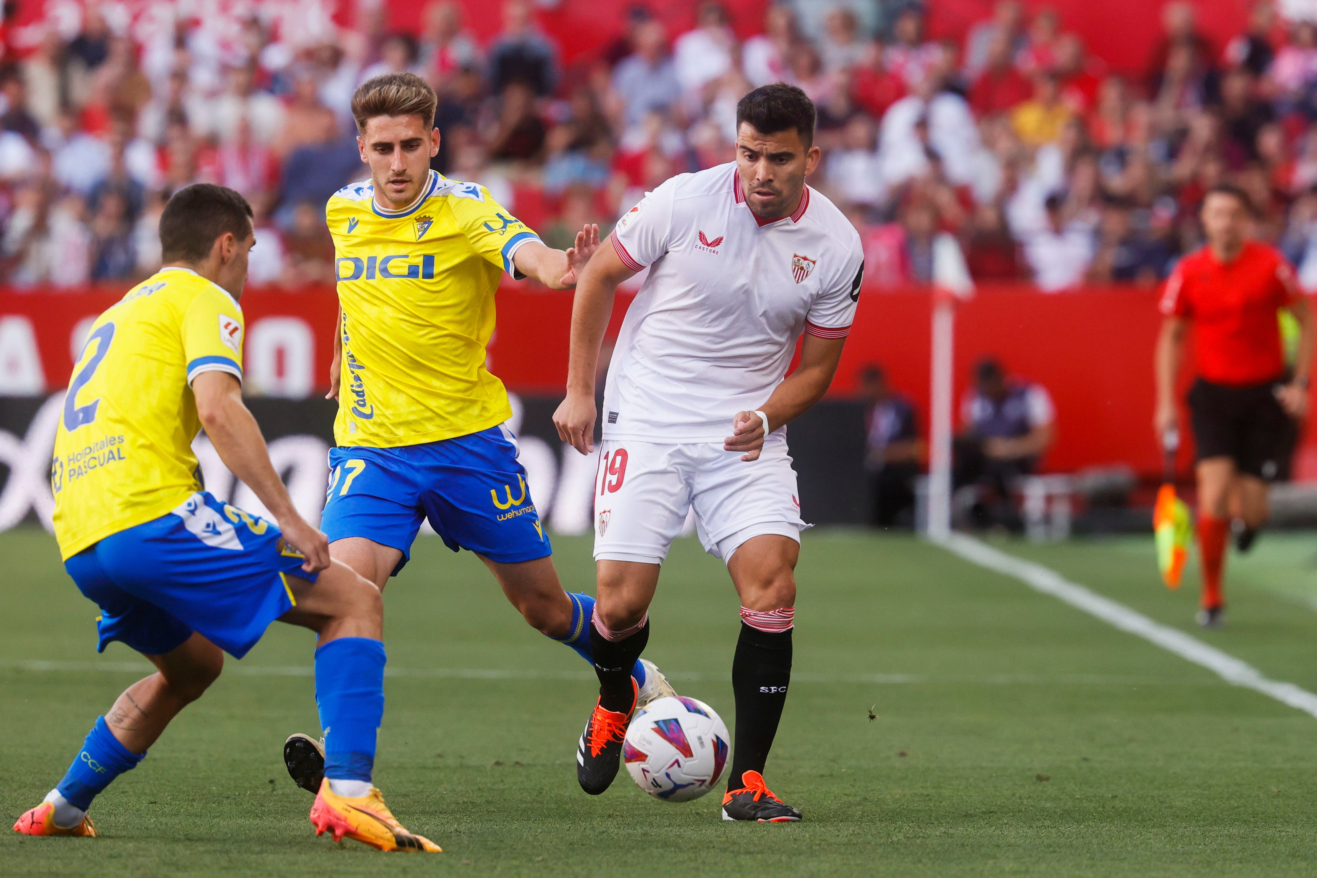 El centrocampista argentino del Sevilla Marcos Acuña (d), el defensa del Cádiz Joseba Zaldua (i) y su compañero Robert Navarro durante el partido de LaLiga disputado entre Sevilla y Cádiz, en el estadio Sanchez Pizjuan de Sevilla (EFE/José Manuel Vidal)
