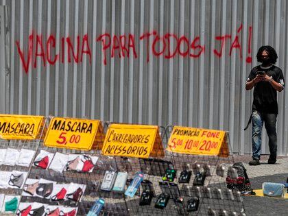 Un hombre camina junto a una pared en la que se lee la frase "vacuna para todos ya!" en Río de Janeiro. EFE/ Antonio Lacerda/ Archivo
