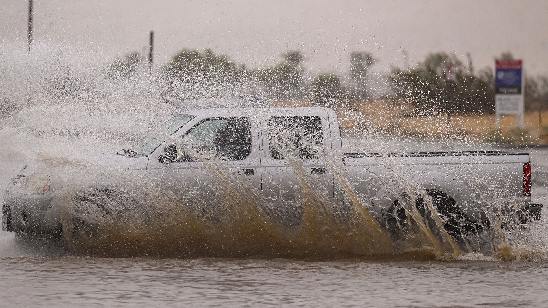 Un vehículo atraviesa una intersección inundada cuando la tormenta tropical Hilary toca tierra en Palm Springs, California.