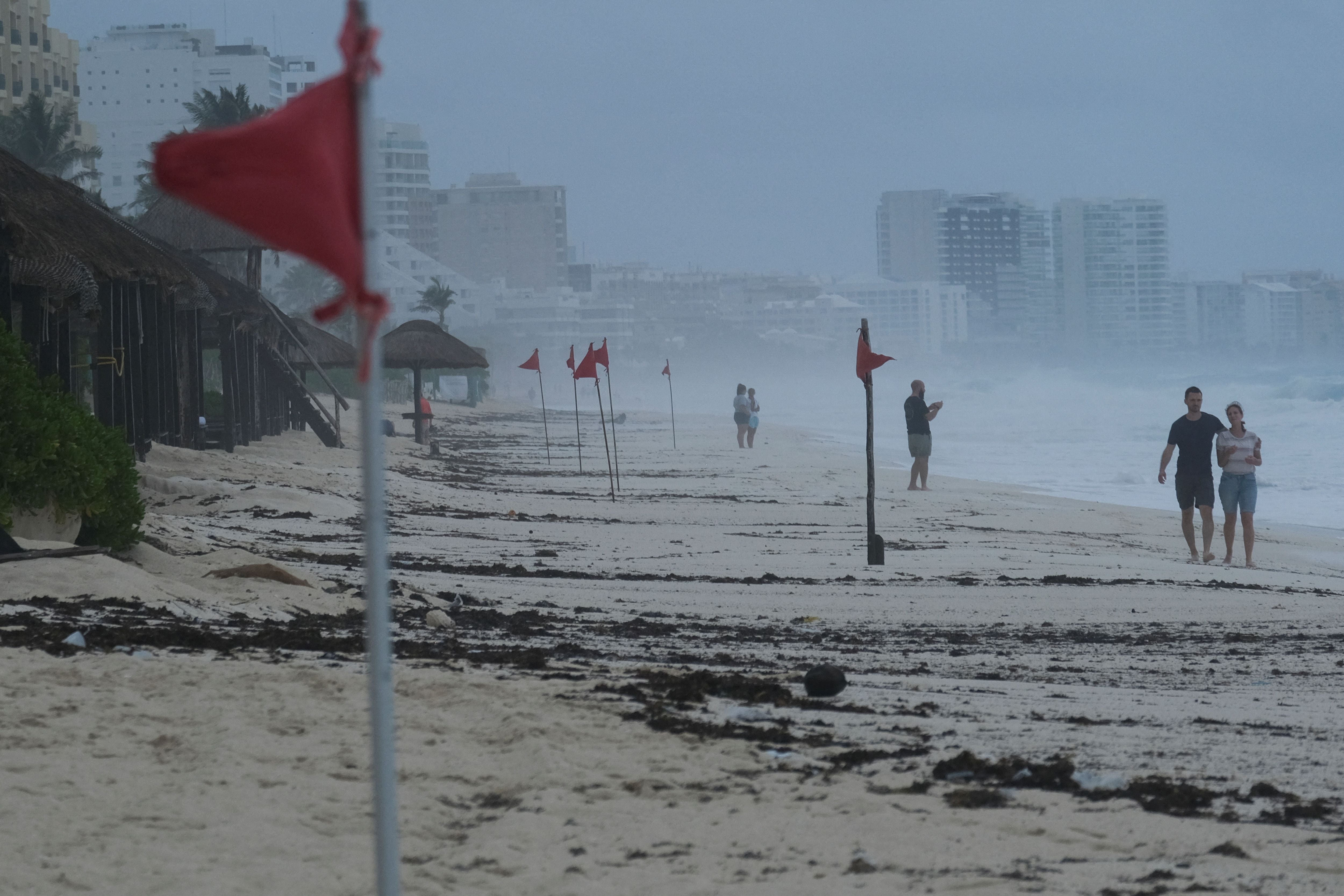 Tourists walk past red flags warning beachgoers of dangerous conditions as Tropical Storm Helene approaches the Yucatan Peninsula, in Cancun, Mexico September 24, 2024. REUTERS/Paola Chiomante