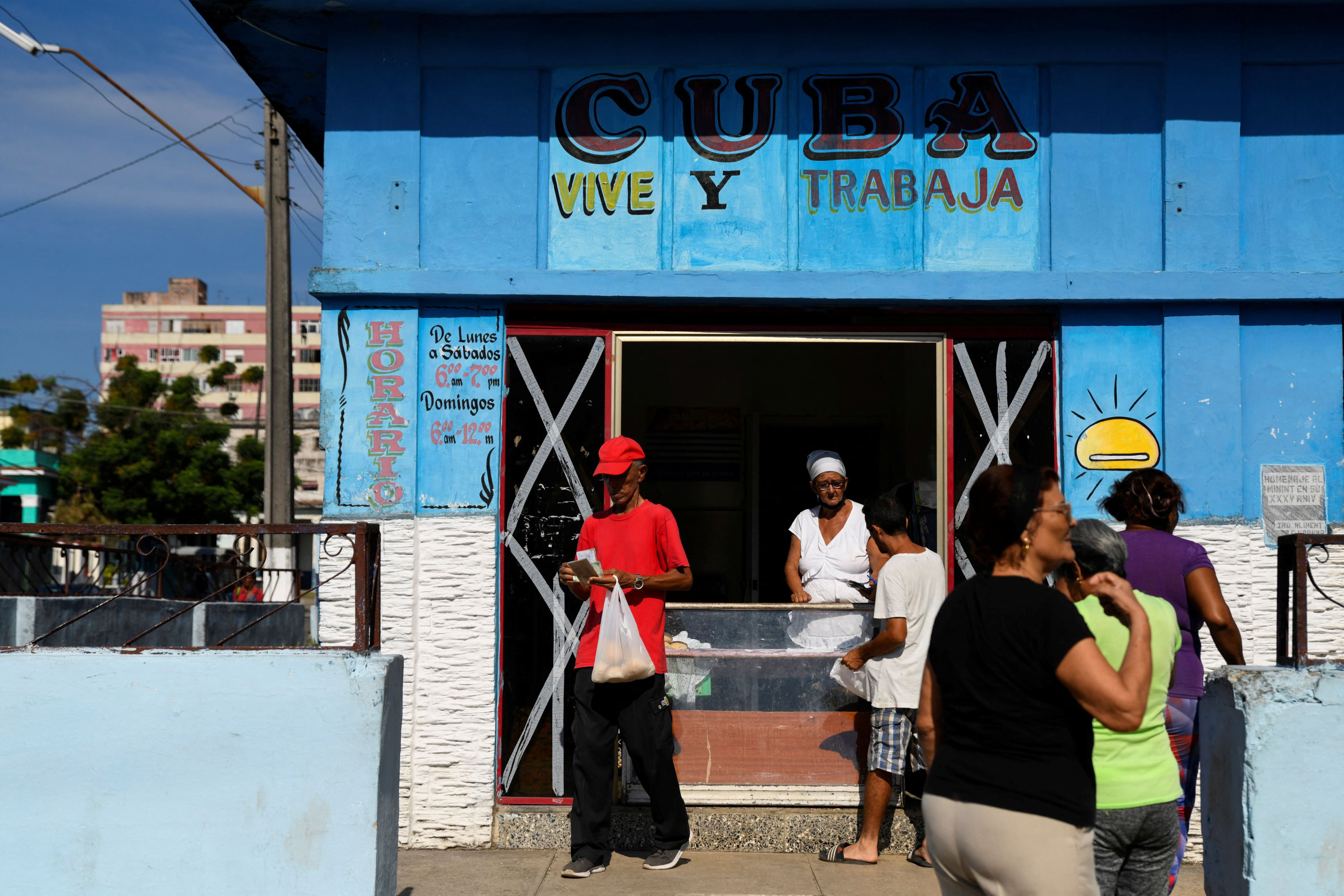 Cubanos compran pan en un comercio de La Habana el 15 de septiembre de 2024. En una pared se lee 