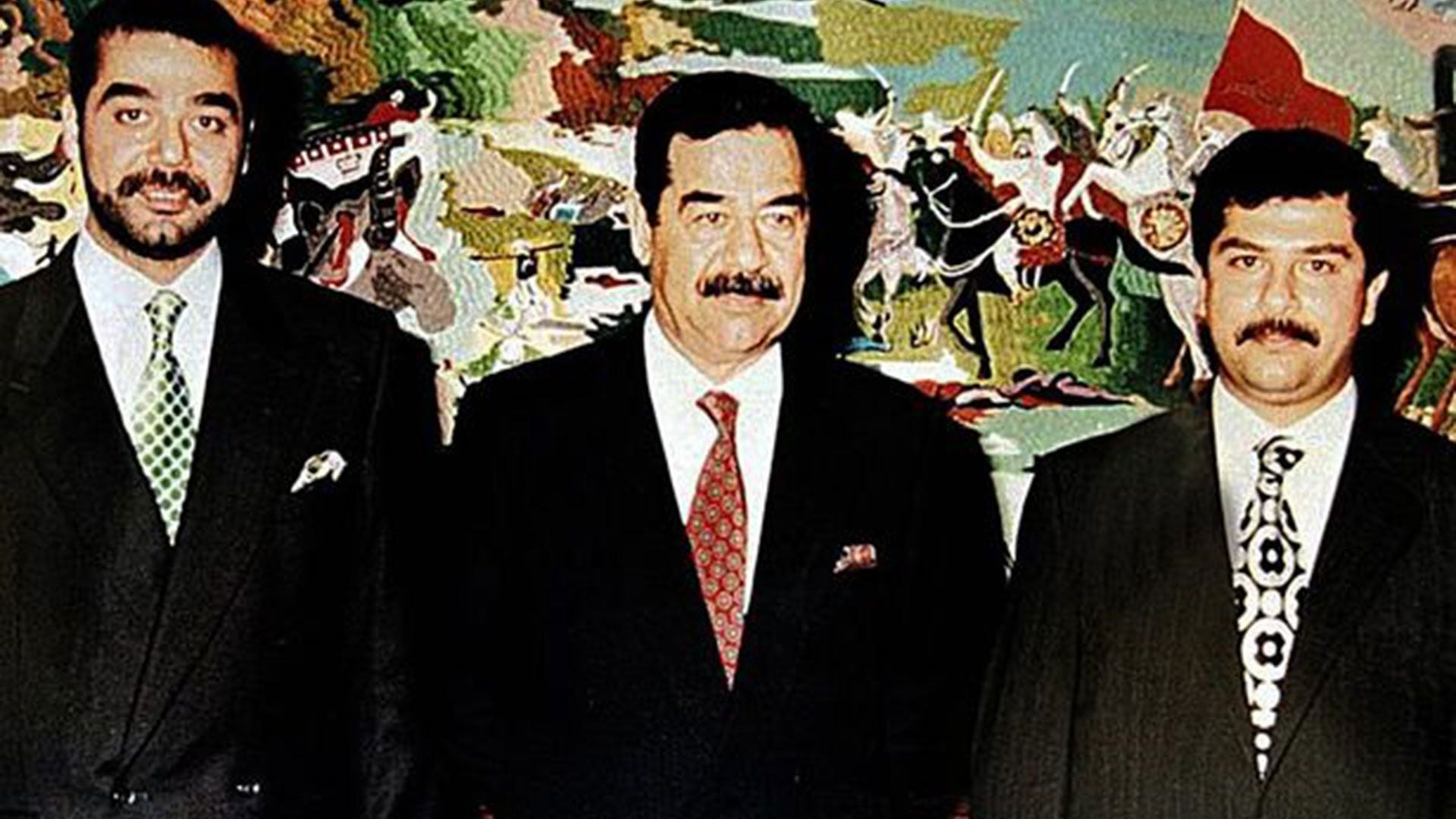 Uday a la izquierda de Saddam Hussein y Qysay a la derecha del dictador iraquí (AFP)