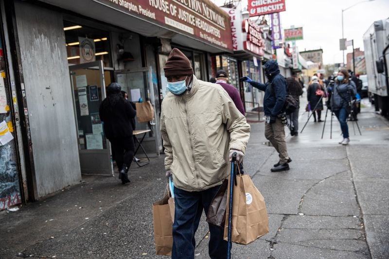 Un hombre con una mascarilla de protección facial traslada raciones de comida gratis en la Ciudad de Nueva York.  EEUU, 18 de abril de 2020. REUTERS/Jeenah Moon