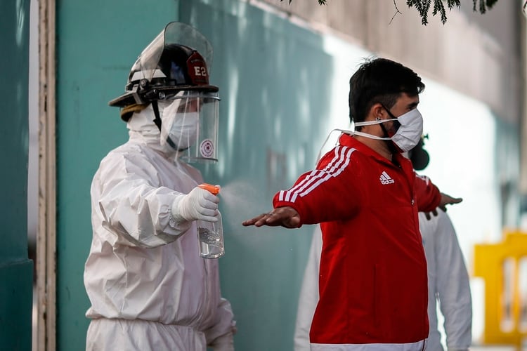 Un bombero rocía con alcohol a un hombre durante una jornada de tomas de pruebas de coronavirus en el barrio Constitución de Buenos Aires. En la actualidad la cantidad de fallecidos por el virus es de 878 (EFE) 