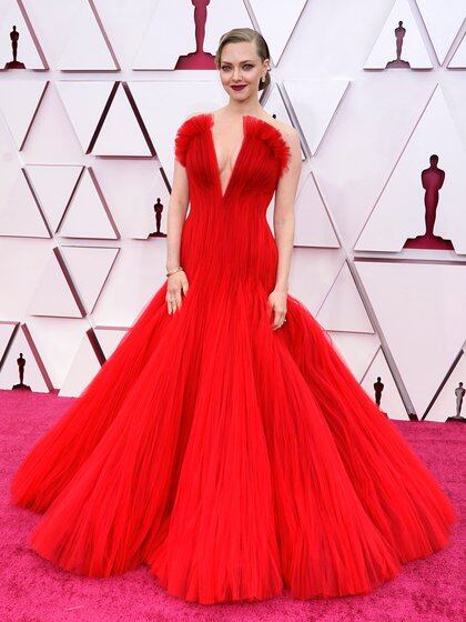 Amanda Seyfried impactó con su vestido firmado por Armani en color rojo. De tul, diseño sirena, gran escote y falda princesa. Completó su look con pendientes, esclavas y para su beauty look cabello recogido y boca color bordó 