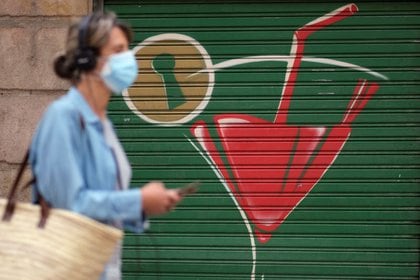 Una mujer con una mascarilla caminando por una calle de Barcelona. 
