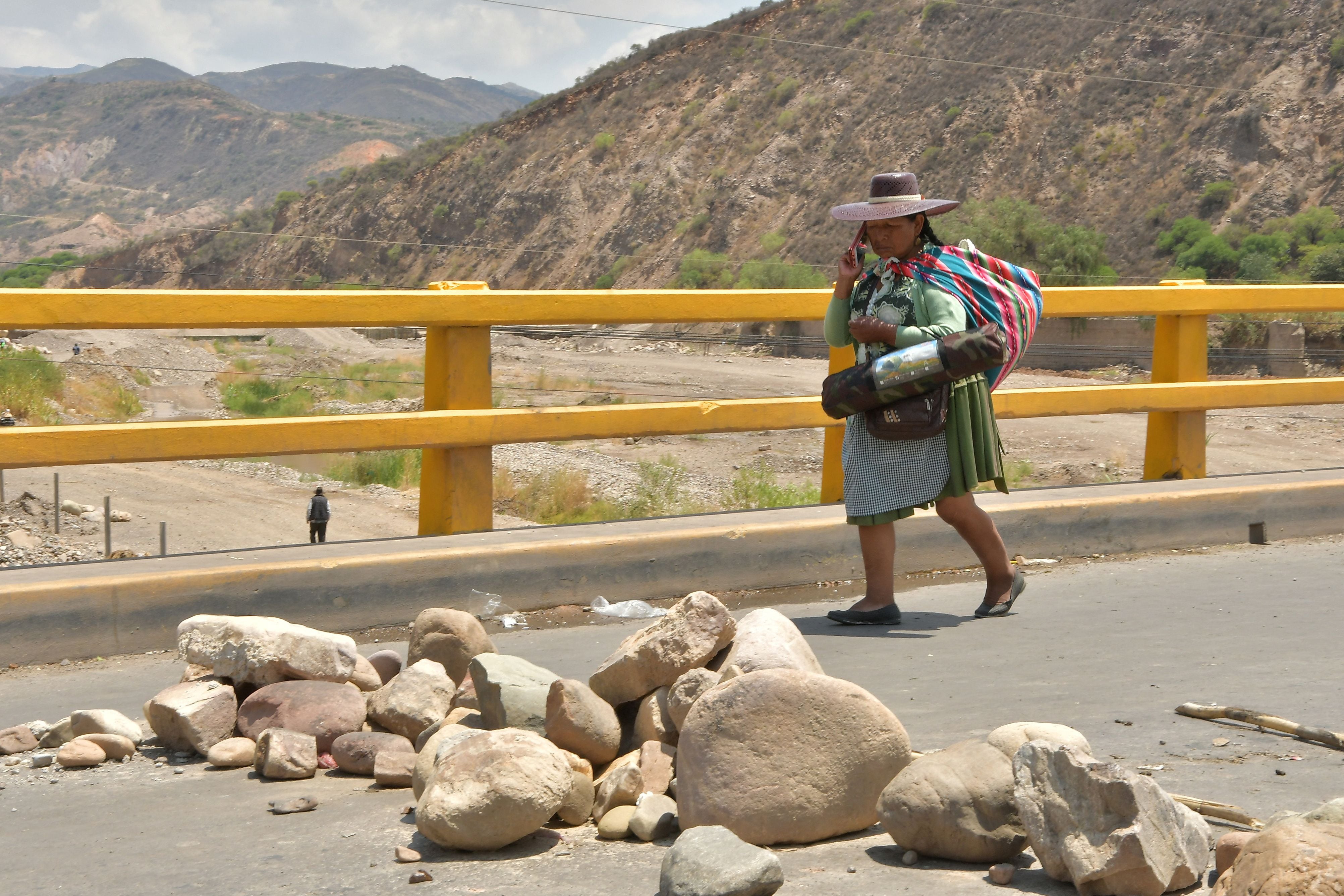 Una mujer camina junto a un bloqueo de carretera establecido por simpatizantes del expresidente de Bolivia Evo Morales (REUTERS/Patricia Pinto) 