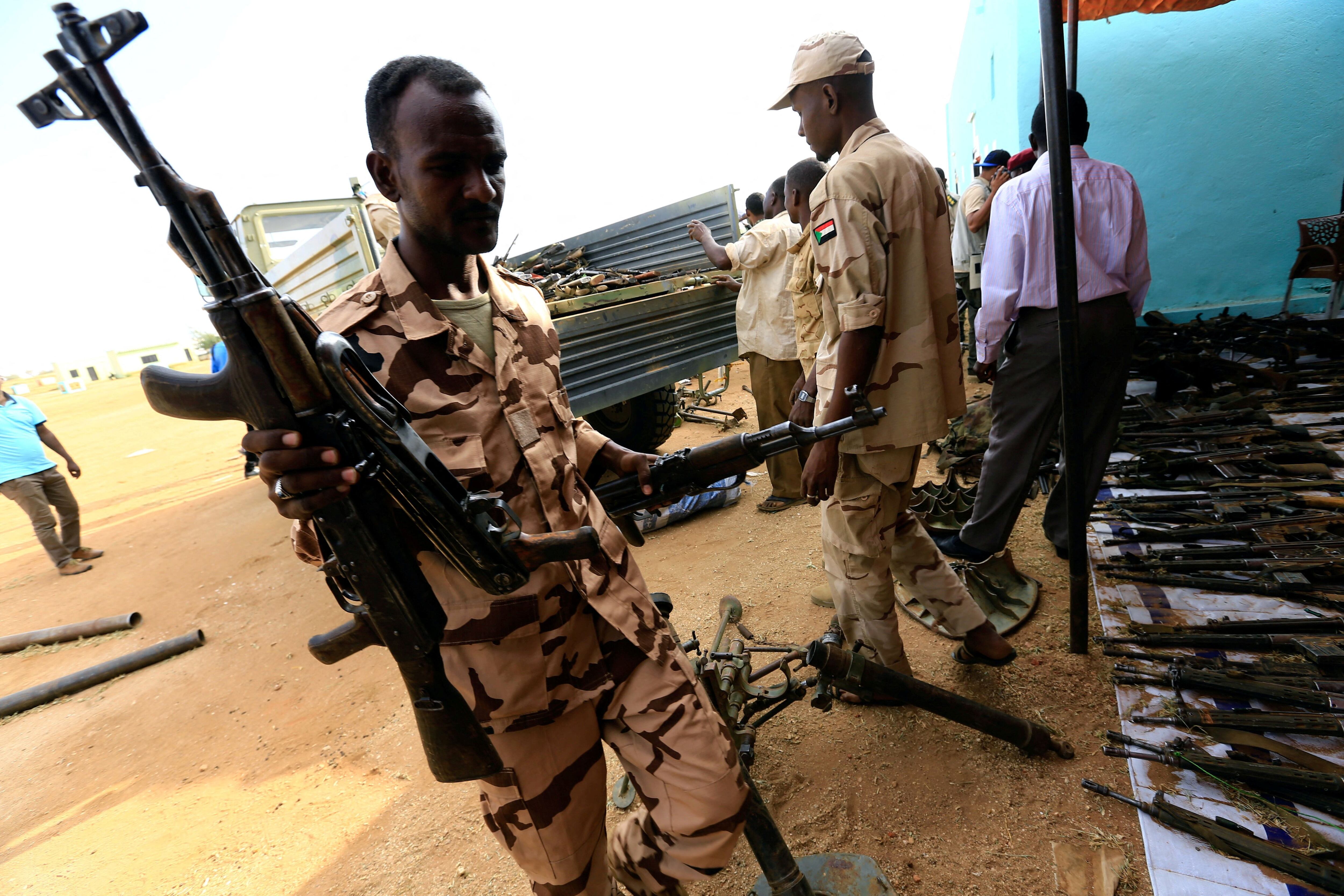 Las Fuerzas de Apoyo Rápido suben armas desarmadas para su exhibición durante la visita del presidente sudanés Omar al-Bashir a la región de Darfur, devastada por la guerra, en el cuartel general del grupo paramilitar en Umm Al-Qura (REUTERS/Mohamed Nureldin Abdallah)