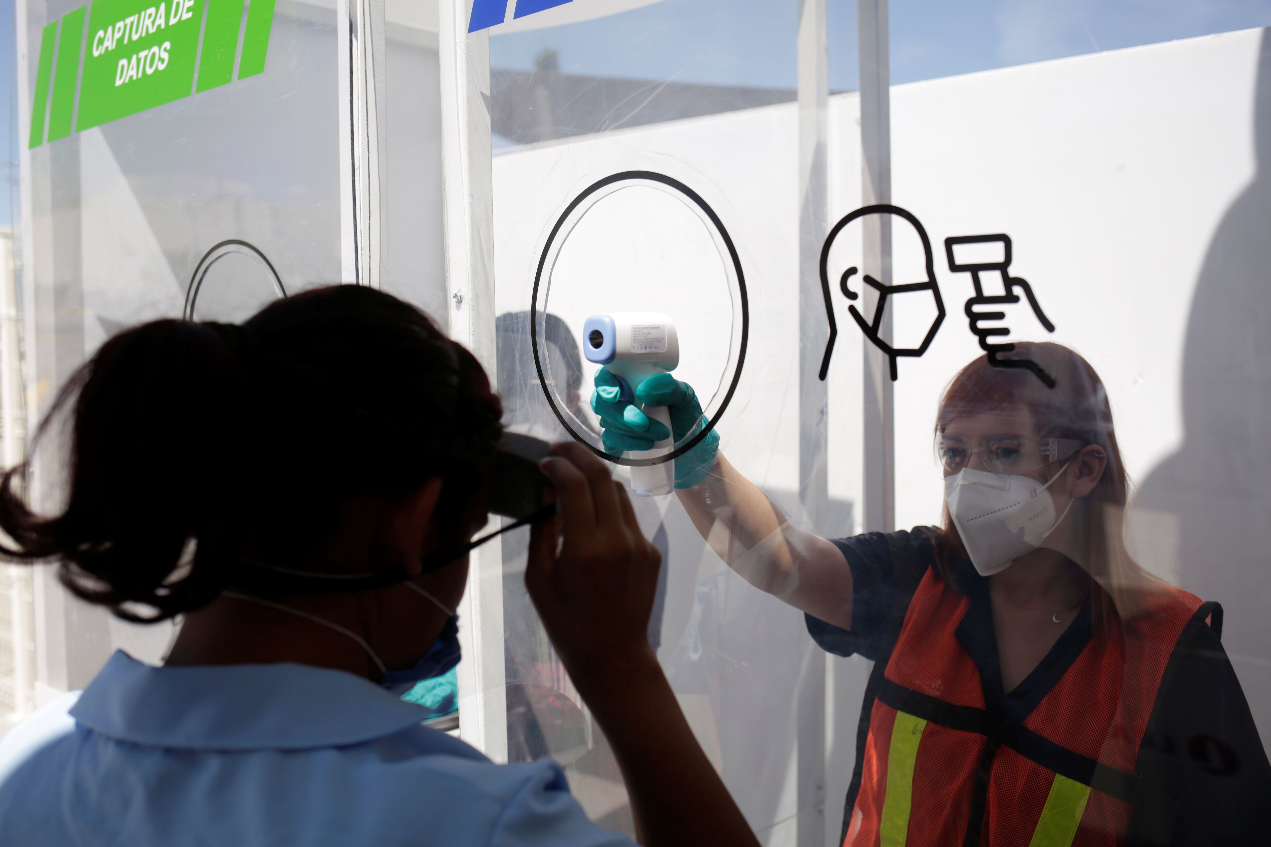 An employee of U.S. auto part maker Lear Corp., has her temperature taken while arriving for a training course to learn the new security measures at the plant before resuming operations during the coronavirus disease (COVID-19) outbreak, in Ciudad Juarez, Mexico, May 27, 2020. Picture taken May 27, 2020. REUTERS/Jose Luis Gonzalez