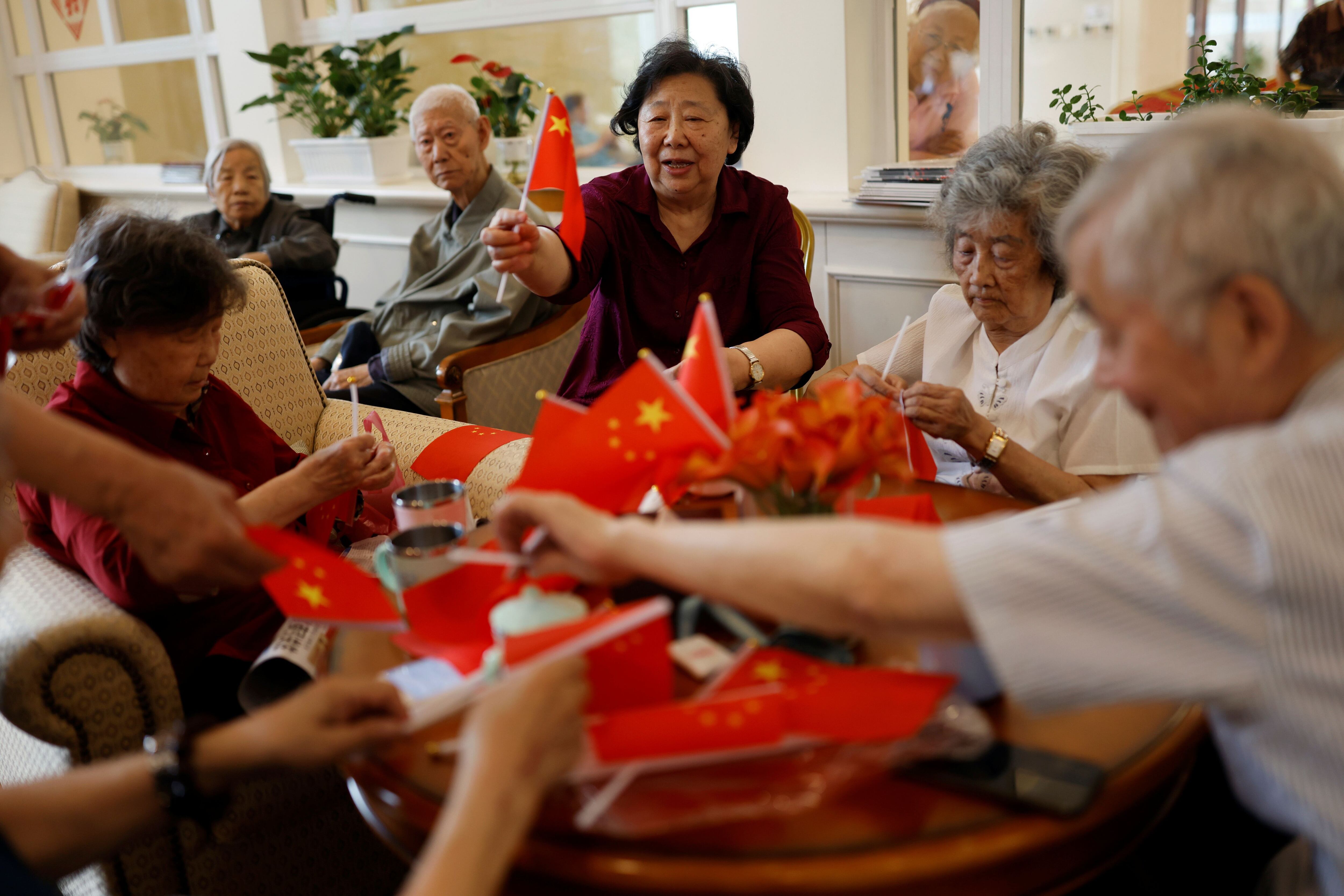 Abuelos reúnen banderas chinas mientras conversa con otras personas mayores en una residencia de ancianos, en Beijing, China. Foto tomada el 26 de mayo de 2021. REUTERS/Carlos García Rawlins